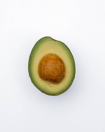 Foto de Un aguacate cortado con su semilla intacta, presentado sobre un fondo blanco para resaltar su vibrante color verde - Imagen libre de derechos