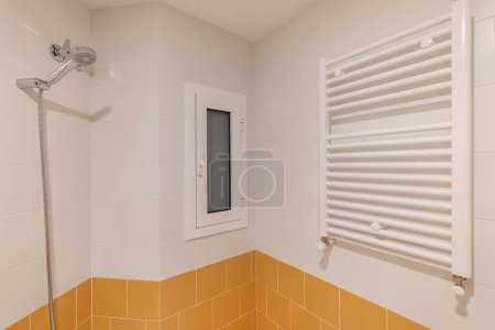 Una vista de esquina de una moderna zona de ducha con un cabezal de ducha portátil y azulejos de dos tonos