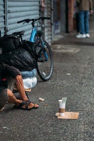 Una franca instantánea de la lucha urbana con una persona sin hogar en medio de la vida de la ciudad.