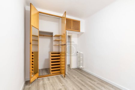 Photo for Living room with an outdated design and white walls, in need of repair, updating appearance. Wardrobe with wooden doors and floor with old parquet. Small area of premises requires cosmetic repairs - Royalty Free Image