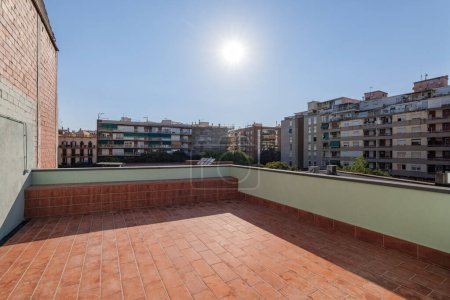 Big sunny terrace on the roof of modern building lined with red brick tiles overlooking the neighboring houses. Summer playground for leisure activities, party and meetings with friends