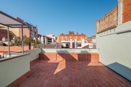 Luxurious terrace on the second floor of a roof lined with red brick tiles overlooking the neighboring houses. Summer playground for leisure activities, party and meetings with friends