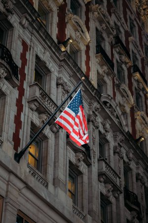 An American flag sways against a backdrop of ornate old-world masonry.