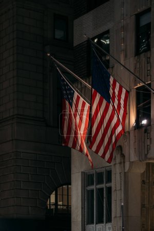 Zwei amerikanische Flaggen wehen in der Nacht auf einem städtischen Gebäude.