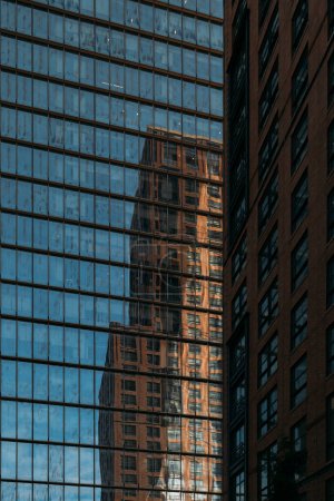 The historic architecture of NYC mirrored in the facade of a modern skyscraper.