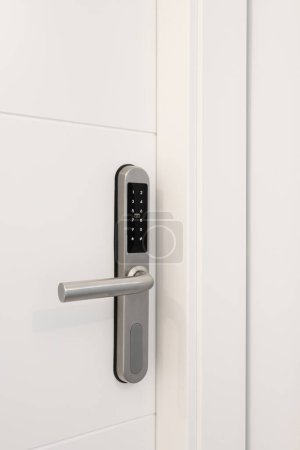 Foto de Entrada puerta de madera blanca con cerradura electrónica para la seguridad del apartamento. En la cerradura hay botones con números para introducir el código. Cerradura de metal cromado - Imagen libre de derechos