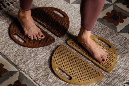 Draufsicht der Füße auf verschiedenfarbigen Sadhu-Brettern gegen vielfältig strukturierte Matten.