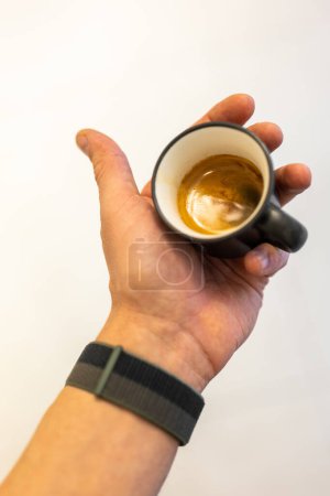 Close-up view of a freshly made espresso held in a persons hand.