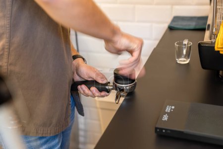 The precise moment a barista secures the portafilter into the espresso machine.