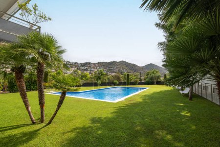 Vistas panorámicas de un jardín sereno con una piscina, rodeado de exuberante vegetación y colinas.