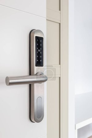 Foto de Entrada puerta de madera blanca con cerradura electrónica para la seguridad del apartamento. En la cerradura hay botones con números para introducir el código. Cerradura de metal cromado - Imagen libre de derechos
