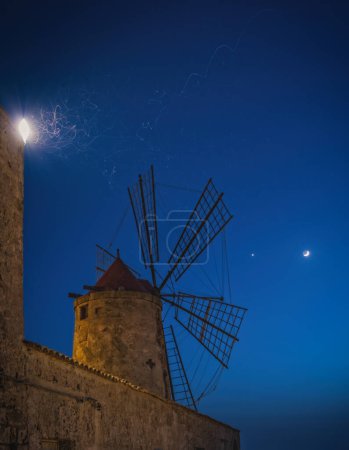 Salt mine and windmill in Trapani at cloudless night. June 2023