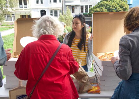 Téléchargez les photos : San Francisco, CA - 22 oct. 2022 : Le personnel du sénateur Scott Wiener servant de la pizza lors de son événement de sculpture de citrouille d'Halloween au parc Noe Courts. - en image libre de droit