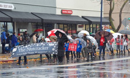 Foto de Benicia, CA - 10 de diciembre de 2022: Participantes no identificados en el Desfile de Navidad anual, con bandas locales de marcha, bailarines y el tan esperado Santa Claus. Caminando bajo la lluvia - Imagen libre de derechos