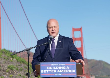 Téléchargez les photos : San Francisco, CA - Jan 23, 2023:  Mitch Landrieu, Senior Advisor to the President on Infrastructure, speaking about the federal gov investments in infrastructure, GGB behind him - en image libre de droit