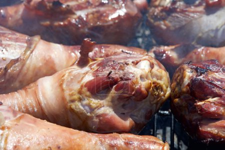 Photo for Turkey legs grilling on a BBQ grill. Giant turkey legs are a very popular food for street fair vendors. - Royalty Free Image