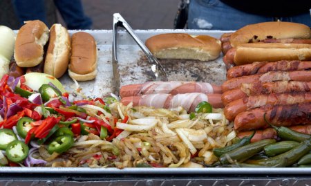 Straßenverkäufer kochen Speck eingewickelte Hotdogs, Zangen drehen Essen. Beliebte Küche für Straßenfeste und Veranstaltungen