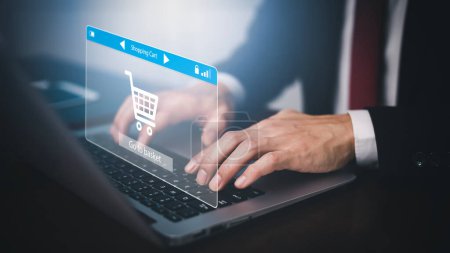 Photo for Man using a laptop with typing on a keyboard with online shopping concept, Shopping cart part of the network in hand, Innovation in eCommerce, Online shopping business with selecting shopping cart. - Royalty Free Image
