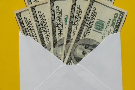 Foto de Dollar banknote saving money in envelope on yellow background copy space. Consumption and economy Collecting money. Tips. Business, finance, saving, banking and people concept. Extra money, passive income. Saving for travel, crisis, house, car, educa - Imagen libre de derechos