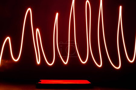 Foto de Abstract red lines drew by using long exposure of camera and flash light shape of graphic. Investing in the online puppet market. Network internet mobile wireless business concept - Imagen libre de derechos