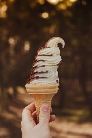 Photo for Female hand holding delicious american vanilla chocolate ice cream. Tasty homemade icecream Gelato in the waffle cone. Gluten free vegan dairy free ice cream. - Royalty Free Image