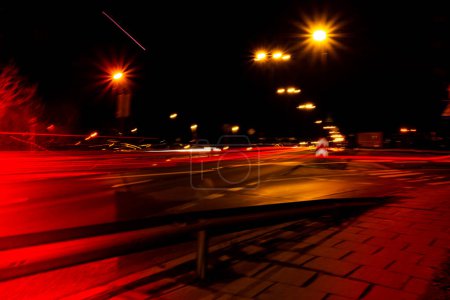 Téléchargez les photos : Lumières de voitures la nuit. Des lampadaires. Nuit autoroute ville. Longue exposition photographie route de nuit. Bandes colorées de sentiers de lumière rouge sur la route. Fond d'écran photo floue déconcentrée - en image libre de droit