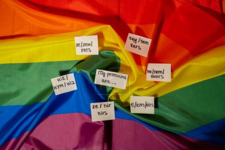 Foto de MIS PRONUNCIAS SON Neo pronombres concepto. Rainbow flag with paper notes text gender pronoms hie, e, ne, xe, ze, tey. Transgéneros no binarios de derechos humanos. El apoyo de la comunidad Lgbtq asume mi género - Imagen libre de derechos