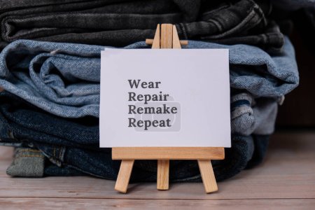 Photo for WEAR REPAIR REMAKE REPEAT text on paper note on Jeans clothes assortment Second hand sustainable shopping. Capsule minimal wardrobe. Sustainable fashion overconsumption, conscious buying consumption - Royalty Free Image