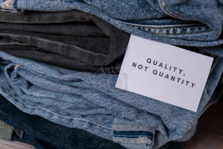 Photo for Quality not quantity text on paper note on Jeans clothes assortment Second hand sustainable shopping. Capsule minimal wardrobe. Sustainable fashion overconsumption, conscious buying consumption, slow - Royalty Free Image