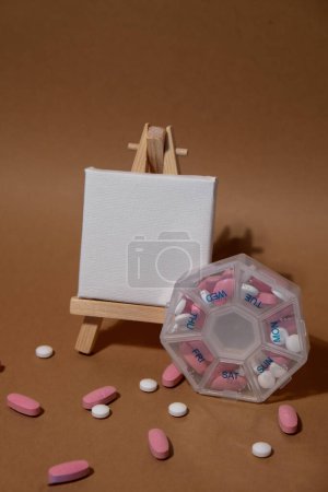 Téléchargez les photos : Closeup of medical pill box with doses of tablets for daily take medicine with white pink drugs and capsules with paper note Copy space for your text template mock up. Daily vitamins at home - en image libre de droit