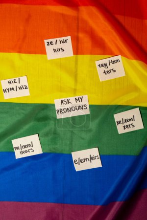 Foto de Pregúntenme mi concepto de pronombres neo. Rainbow flag with paper notes text gender pronoms hie, e, ne, xe, ze, tey. Transgéneros no binarios de derechos humanos. El apoyo de la comunidad Lgbtq asume mi género - Imagen libre de derechos