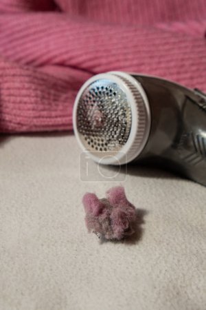 Photo for Anti-pilling razor. Device for shaving clothes. Anti-Plush fabric Shaver. Electric portable sweater pill defuzzer Lint remover from pink acrylic or wool sweater. Electric device fabric shaver after - Royalty Free Image