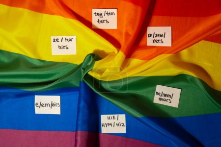 Foto de Concepto de pronombres neo. Rainbow flag with paper notes text gender pronoms hie, e, ne, xe, ze, tey. Transgéneros no binarios de derechos humanos. El apoyo comunitario de Lgbtq asume mi género, respeta los pronombres - Imagen libre de derechos