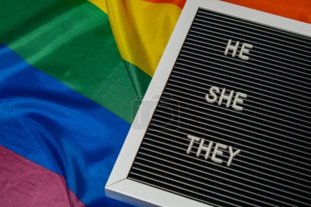 HE SHE THEY text Neo pronouns concept on Rainbow flag background gender pronouns. Non-binary people rights transgenders. Lgbtq community support assume my gender, respect pronouns tolerance equal