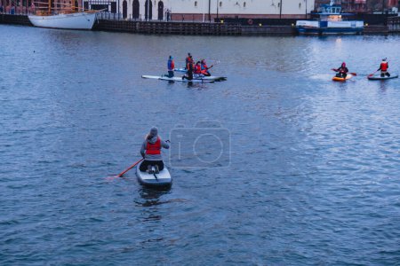 Photo for Gdansk Poland March 2022 Group of sup surfers stand up paddle board, paddling together in the city Motlawa river and canal in old town evening dusk. Tourism attraction Active outdoor - Royalty Free Image