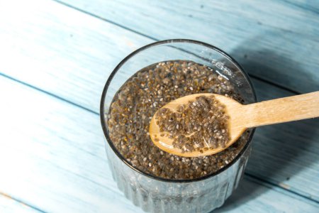 Photo for Preparing superfood water drink rich in Omega 3 fatty acids. Pouring coconut water. Adding soaked chia seeds and lemon detox Breakfast. Clean eating, weight loss, dieting food concept Vegetarian - Royalty Free Image
