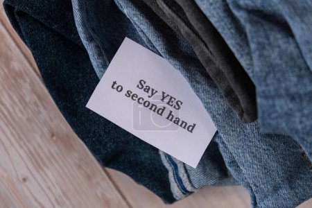 Photo for SAY YES TO SECOND HAND text on paper note on Jeans clothes assortment Second hand sustainable shopping. Capsule minimal wardrobe. Sustainable fashion overconsumption, conscious buying consumption - Royalty Free Image