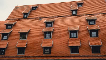 Téléchargez les photos : Coin avec lucarnes Toits rouges de la ville tuiles métalliques brun toit de la maison européenne avec fenêtres. Typique toiture européenne en brique avec fenêtres. Bydgoszcz ville - en image libre de droit
