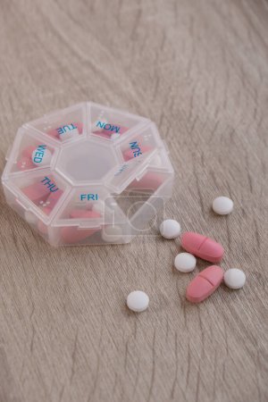 Photo for Organizer weekly shots Closeup of medical pill box with doses of tablets for daily take medicine with white pink drugs and capsules. Daily vitamins at home. Medication dietary supplements, immunity - Royalty Free Image