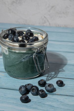 Photo for Glass jar with natural organic homemade yogurt and blueberries spirulina chlorella superfood super powder blue algae sea weed. Immunity-boosting ingredients. Concept of healthy eating breakfast of - Royalty Free Image
