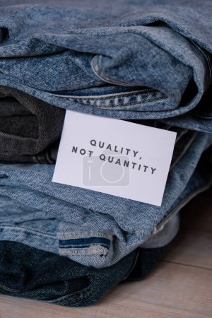 Photo for Quality not quantity text on paper note on Jeans clothes assortment Second hand sustainable shopping. Capsule minimal wardrobe. Sustainable fashion overconsumption, conscious buying consumption, slow - Royalty Free Image