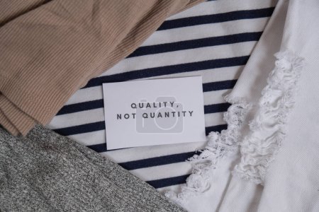 Photo for Quality not quantity text on paper note on clothes assortment Second hand sustainable shopping. Capsule minimal wardrobe. Sustainable fashion overconsumption, conscious buying consumption, slow - Royalty Free Image