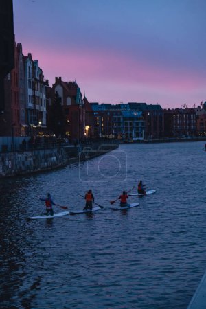 Photo for Gdansk Poland March 2022 Group of sup surfers stand up paddle board, paddling together in the city Motlawa river and canal in old town evening dusk. Tourism attraction Active outdoor - Royalty Free Image