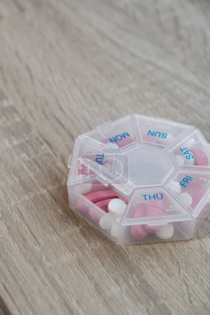 Téléchargez les photos : Organizer weekly shots Closeup of medical pill box with doses of tablets for daily take medicine with white pink drugs and capsules. Daily vitamins at home. Medication dietary supplements, immunity - en image libre de droit