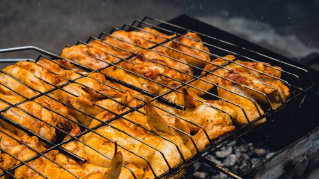 Photo for BBQ picnic time Roasted chicken legs and wings on grill. Grilling meat on outdoor grill grid tasty barbeque chicken steak with smoke flames juicy meat in the backyard in summer - Royalty Free Image