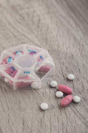 Téléchargez les photos : Organizer weekly shots Closeup of medical pill box with doses of tablets for daily take medicine with white pink drugs and capsules. Daily vitamins at home. Medication dietary supplements, immunity - en image libre de droit