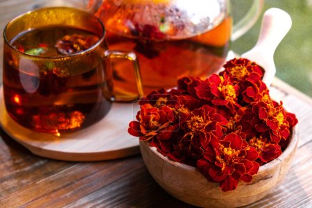 Téléchargez les photos : Souci fleur thé sain dans une tasse en verre avec pot à thé sur la table de jardin. Médecine à base de plantes Délicieux tisane thé avec fleur jaune fraîche pissenlit fleurs tasse de thé. Infusion de clairière verte Fleurs sauvages Eco - en image libre de droit