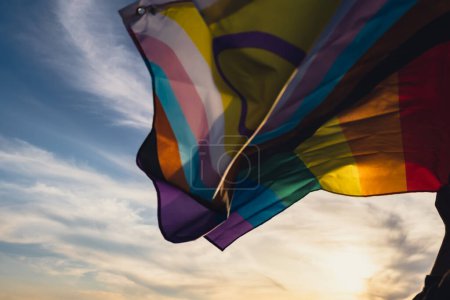 Foto de Identidad de género. Bandera Rainbow LGBTQIA desenfocada ondeando en el viento hecha de material de seda sobre el fondo del campo. Símbolo del mes del orgullo LGBTQ. La igualdad de derechos. Concepto paz y libertad - Imagen libre de derechos