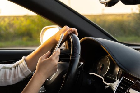 Frau verschickt während Autofahrt Nachrichten mit Smartphone. Autofahrerin während der Fahrt mit Handy unterwegs Sicherheits- und Technologiekonzept 