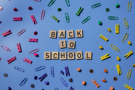 BACK TO SCHOOL message inscription text on wooden blocks on creative colorful blue background with stationery supplies around. Educational greeting announcement for students and teacher. Top view flat